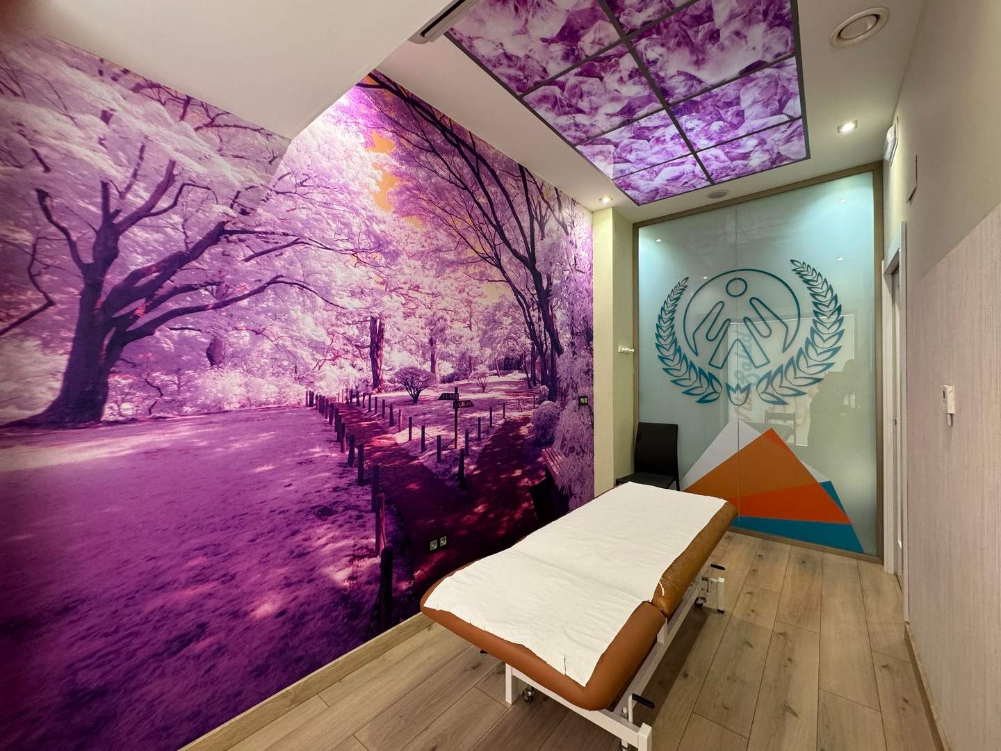 Sala de tratamiento con mural morado de árboles y techo LED retroiluminado